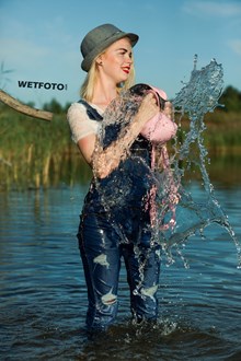 #415 - Joyful Blonde Girl in Jeans Jumpsuit, T-shirt, Hat and Shoes Get Wet on the Lake